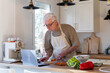 © Alba Vitta/Stocksy - Senior man cooking with online tutorial on laptop