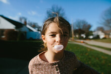 Portrait Of A Girl Blowing A Bubble With Bubble Gum Outside