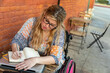 © Jayme Burrows/Stocksy - Disabled Woman Writes in Journal at a Cafe