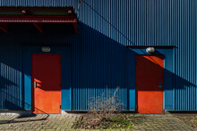 Two Red Doors On A Blue Colored Aluminum Building 