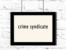 Black Frame Hanging On White Brick Wall With Inscription Crime Syndicate