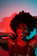 © Mauro Grigollo/Stocksy - Smiling woman in a red and blue light