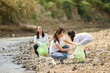© sutlafk - Group of volunteer people collecting trash near river. Ecology charity and clean environment concept