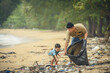 © sutlafk - Asian father and son of volunteer people collecting trash on beach. Ecology charity and clean environment concept.