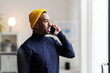 © Studio Marmellata/Stocksy - Modern man in bright hat talking on smartphone at home
