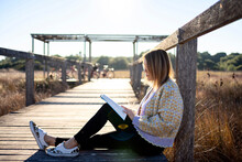 Peaceful Lady Reading Novel On Boardwalk In Countryside