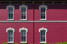 An Old Magenta Brick Building With White Windows 