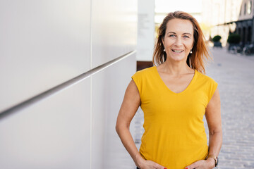 elder woman standing next a gray wall with copy space