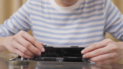 Close-up hand of woman repairing or installing Random Access Memory (RAM) on computer motherboard.