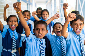 Group of cheerful students shouting by looking camera at school corridor - conept of innocence, freedom and relaxation