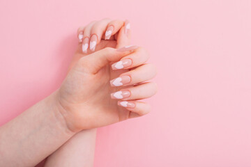 female hands with beautiful long nails with  manicure with  heart pattern on pink background