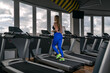 © somemeans - Sports blonde girl running on the treadmill in the empty modern gym. Cardio workout on running track
