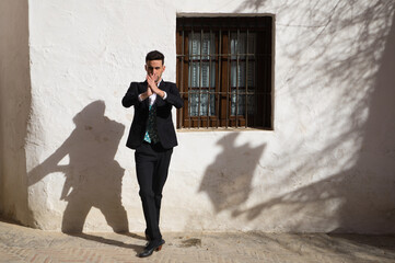 Portrait of young and handsome gipsy man dancing flamenco, dressed in black and green waistcoat dancing flamenco in the typical mediterranean streets of seville. Flamenco cultural heritage of humanity