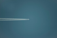 Airplane With White Condensation Tracks. Jet Plane On Clear Blue Sky With Vapor Trail.