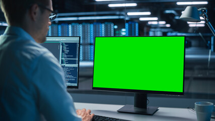 Poster - Confident male Data Scientist Works on Personal Computer with Green Screen Mock Up in Big Infrastructure Control and Monitoring Room with Neural Network. Man Engineer in an Empty Office