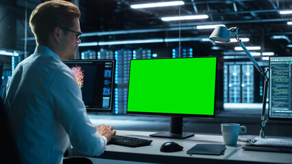 Poster - Data Center: Male Office Worker Using Computer with Green Screen Mock Up in Surveillance Center in a Monitoring Office. Specialist Works in Front of Chroma Key Display.