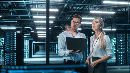 Successful Data Center IT Specialist Using Laptop Computer. Server Farm Cloud Computing Facility with System Administrator Working. Data Protection Engineering Network for Cyber Security.