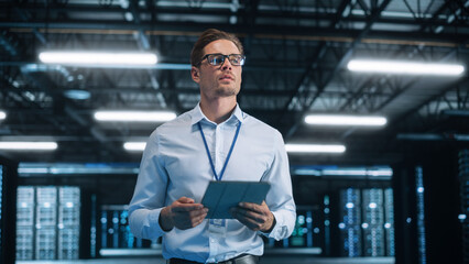 Poster - Caucasian Data Center IT Technician Standing at the Server Rack Corridor with a Tablet Computer. He is Visually Inspecting Something while Looking Away. Night Office Concept