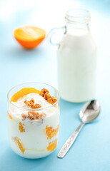 Wall Mural - Greek yogurt with orange and walnuts in glasses on a blue table. Healthy food. Health eating concept. Selective focus.