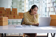 © Wasan - A young woman starting an online business works on her laptop and waits for orders.