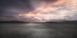 canvas print picture - Dunkler Asphalt Beton Boden Hintergrund mit Abendrot Wolken Himmel und Berge am Horizont