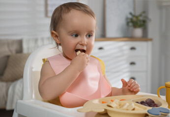 Cute little baby wearing bib while eating at home