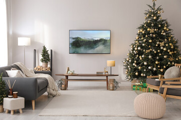 Modern TV set on light wall in room decorated for Christmas