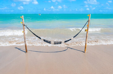 Wall Mural - Hammock in front of the beach, travel concept for rest in a quiet place amidst nature. Photo taken at Barra Grande beach, Maragogi, AL, Brazil.