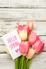 Wall Mural - Card with text HELLO SPRING and bouquet of tulip flowers on light wooden background, closeup