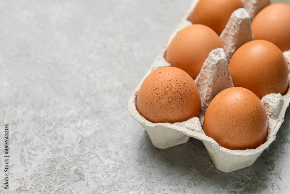Holder with fresh chicken eggs on grey background, closeup