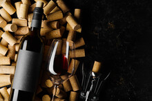 Festive Composition. A Bottle Of Red Wine, A Corkscrew And A Wine Glass Lie On Wine Corks On A Black Background. There Is Free Space To Insert. Holiday, Celebration, Date, Romantic Evening. Banner.
