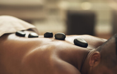 Wall Mural - Do yourself and your body a favour. Cropped shot of a man getting a hot stone massage at a spa.