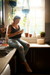 © Chanelle M/peopleimages.com - Whatever she needs her smartphones got her covered. Shot of a young woman using a smartphone in the kitchen at home.