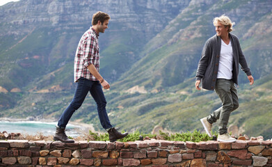 Poster - Bonding with my buddy outdoors. Shot of two young men walking on a stone wall with the mountain in the background.