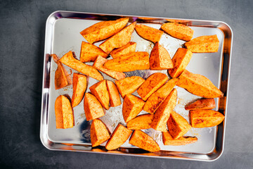 Wall Mural - Raw Sweet Potato Wedges on a Sheet Pan: Uncooked sweet potato wedges seasoned with olive oil, cumin, and smoked paprika