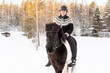 © AnttiJussi - Icelandic horse ride in deep snow. Female rider with Icelandic sweater and helmet.