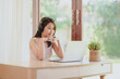 © interstid - Smiling Asian woman wear headphones video conference on laptop for study or working at home