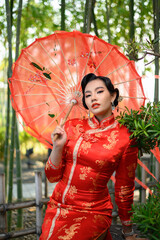 Asian pretty Chinese woman dress traditional cheongsam pose with red umbrella