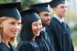 © Nicola Katie/peopleimages.com - Looking forward to their future. Young college graduates holding their diplomas while standing in a row and smiling.