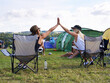 Happy campers. Rearview shot of two friends giving each other a high five at an outdoor festival.