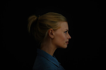 Brodd. A young woman in a denim shirt against a dark background.