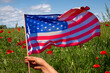 American flag waved by a hand in a poppy field
