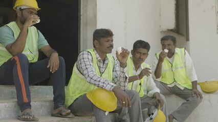 Wall Mural - group of industrial workers having tea or coffee during break - concept of relaxation, coworkers and