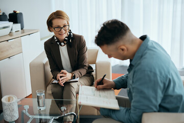 Wall Mural - Happy mental health professional having counseling with patient in her office.