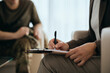 © Drazen - Close up of psychotherapist takes notes during counseling with soldier.