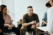 © Drazen - Military officer listens to therapist during group therapy meeting at community center.