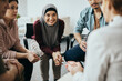 Happy Muslim woman and attenders of group therapy talk with their psychotherapist during meeting at communicatee center.