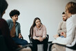 © Drazen - Young woman talks while having group therapy meeting at mental health center.