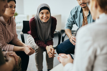 Wall Mural - Happy Muslim woman and attenders of group therapy talk with their psychotherapist during meeting at communicatee center.