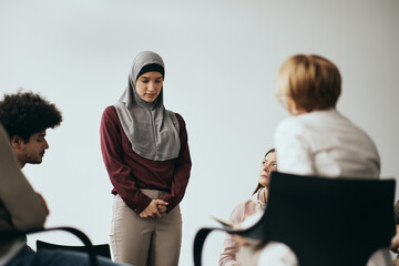 Wall Mural - Anxious Middle Eastern woman talks about her mental health issues during group therapy meeting.